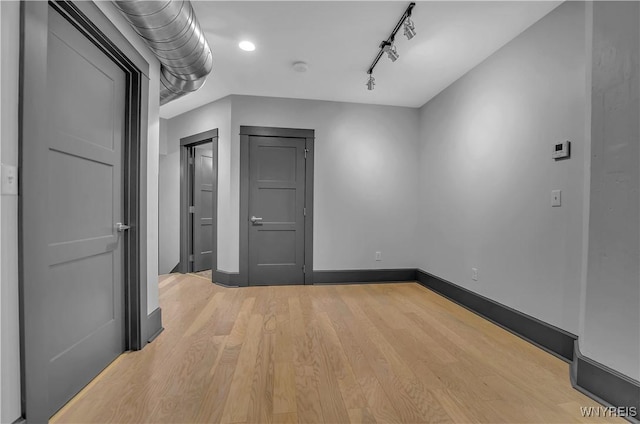 spare room with track lighting and light hardwood / wood-style flooring