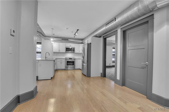 kitchen featuring backsplash, hanging light fixtures, light hardwood / wood-style floors, white cabinetry, and stainless steel appliances