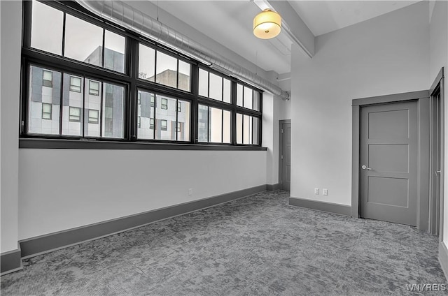 empty room with carpet floors and a towering ceiling