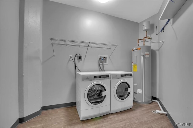 laundry area featuring electric water heater, light hardwood / wood-style floors, and washing machine and clothes dryer