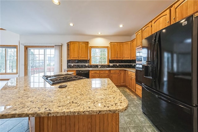 kitchen with black appliances, plenty of natural light, a center island, and backsplash