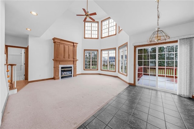 unfurnished living room with ceiling fan, dark carpet, a fireplace, and a wealth of natural light