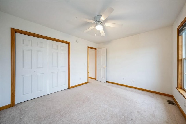 unfurnished bedroom with ceiling fan, light carpet, and a closet