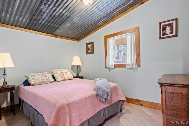 bedroom featuring baseboards, lofted ceiling, and wood finished floors