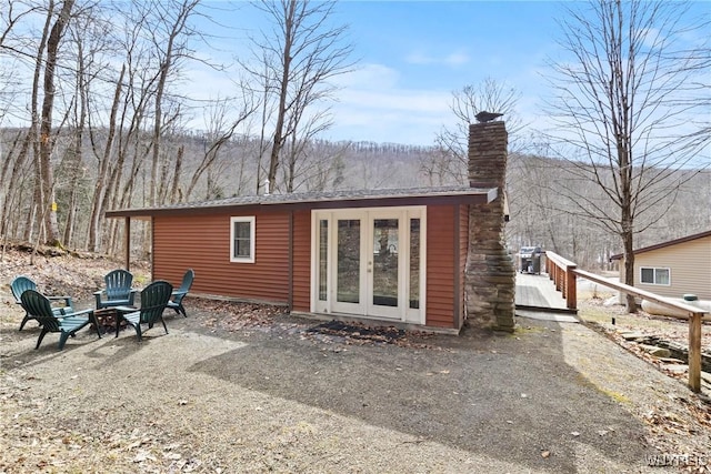 back of property featuring a fire pit, french doors, and a chimney