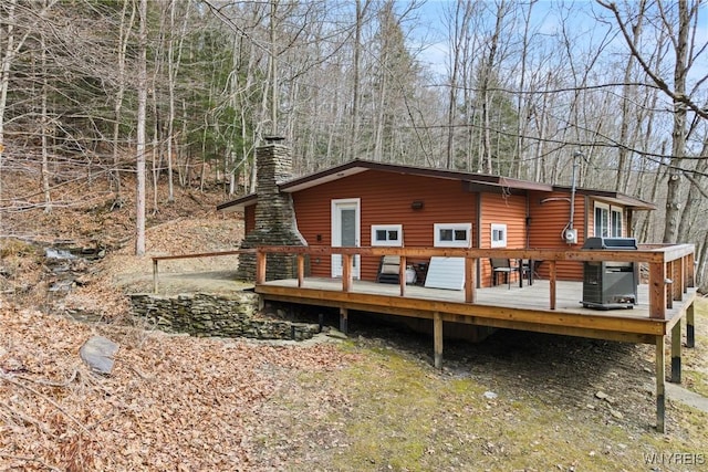 back of house with a wooden deck, central AC unit, and a chimney