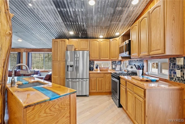 kitchen with light countertops, light wood-style flooring, wooden ceiling, appliances with stainless steel finishes, and a sink