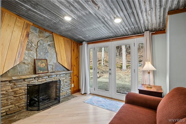 doorway with a stone fireplace, wood ceiling, and wood finished floors