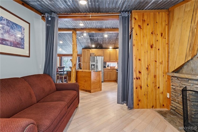 living room featuring wooden ceiling, beamed ceiling, a fireplace, and light wood-type flooring