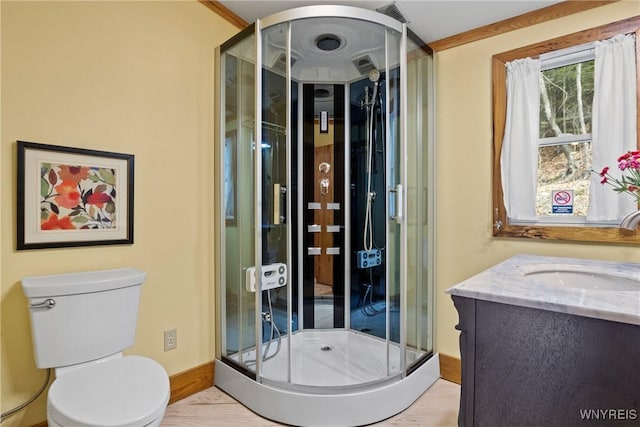 bathroom with visible vents, toilet, a stall shower, wood finished floors, and vanity