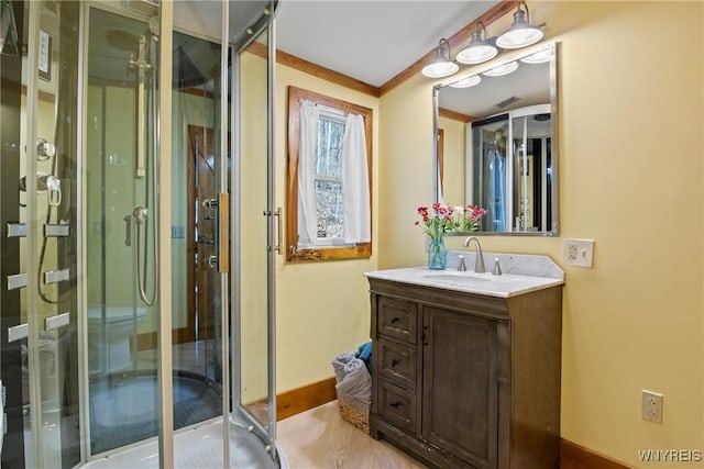 bathroom featuring a stall shower, vanity, baseboards, and wood finished floors