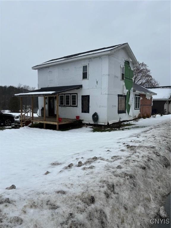 snow covered house featuring a porch