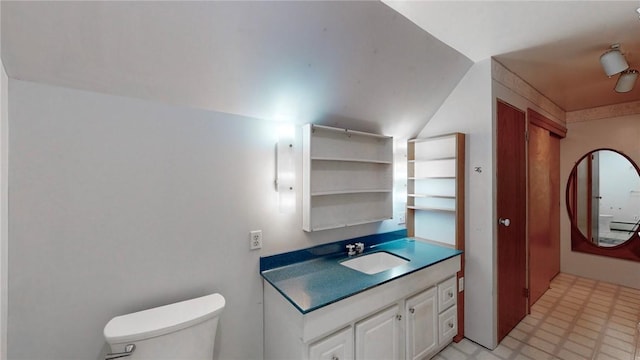 bathroom featuring vanity, toilet, and vaulted ceiling