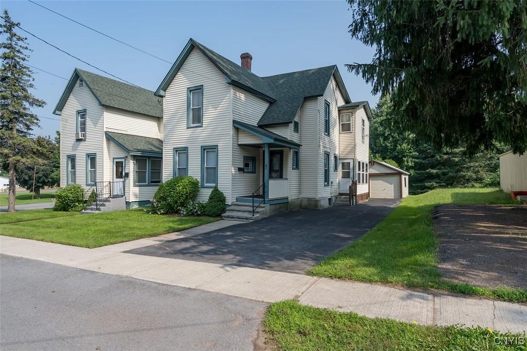 view of front of home featuring a garage, an outbuilding, and a front yard