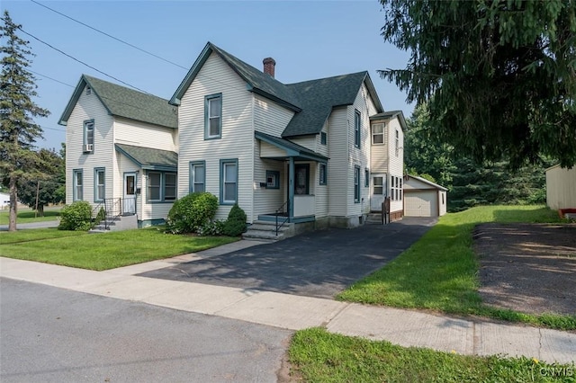 view of front of home featuring a garage, an outbuilding, and a front yard