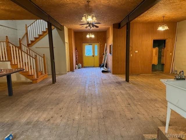 interior space with beam ceiling, wood-type flooring, and an inviting chandelier