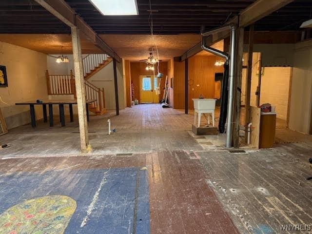 basement with a notable chandelier, wood-type flooring, and sink