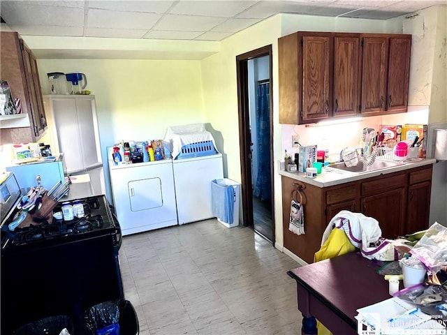 kitchen with black range with electric stovetop, a drop ceiling, washing machine and dryer, and sink