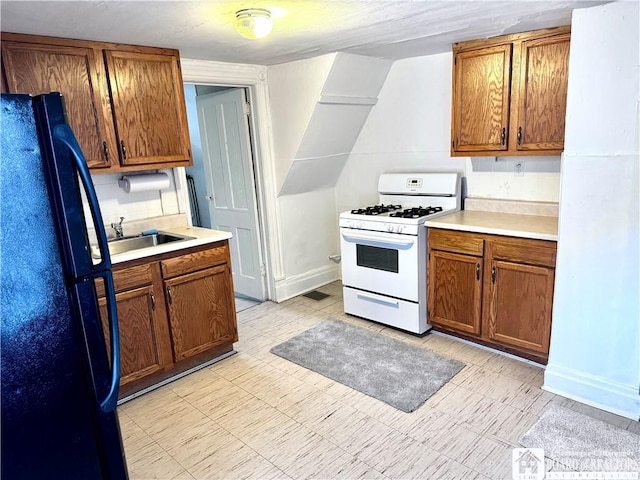 kitchen featuring black fridge, sink, and white range with gas cooktop