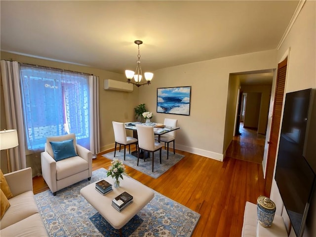 living room featuring a wall mounted AC, an inviting chandelier, ornamental molding, and hardwood / wood-style flooring