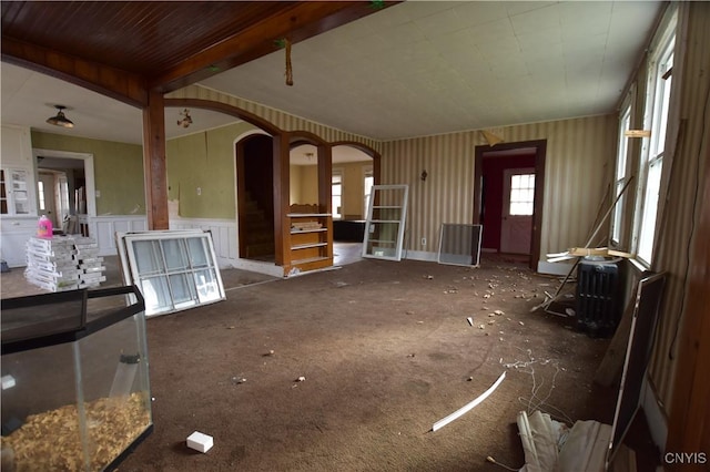 228 Main St, Theresa, NY 13691 - unfurnished living room with arched walkways, a wainscoted wall, and carpet flooring