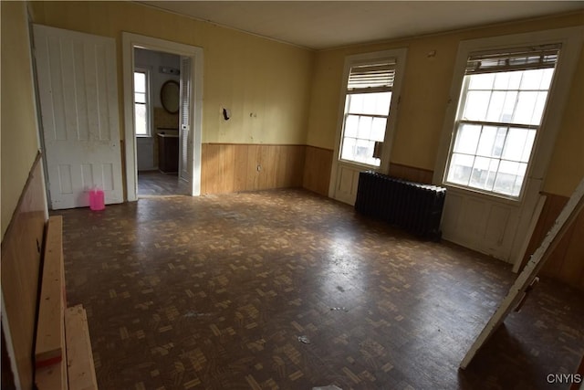 spare room with radiator heating unit and wooden walls