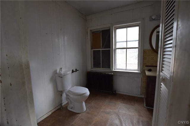 bathroom with toilet, radiator, and wood walls