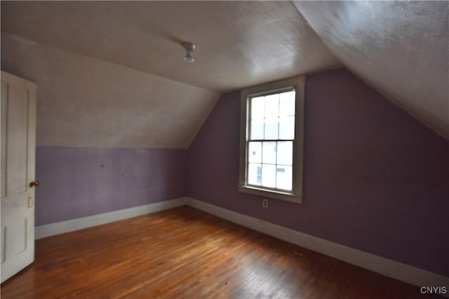 additional living space with dark hardwood / wood-style floors and vaulted ceiling