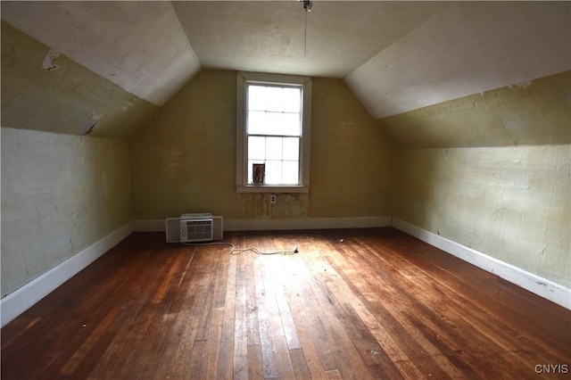 additional living space with a wall unit AC, dark hardwood / wood-style flooring, and lofted ceiling