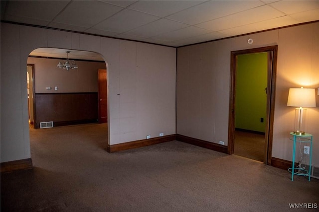 empty room featuring carpet flooring, a drop ceiling, and an inviting chandelier