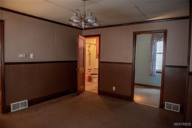 empty room featuring a paneled ceiling, a notable chandelier, and dark colored carpet