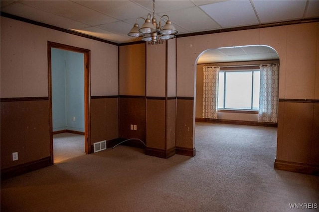 empty room featuring carpet flooring, a drop ceiling, and a notable chandelier