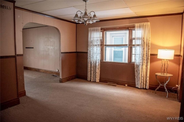 carpeted spare room featuring an inviting chandelier