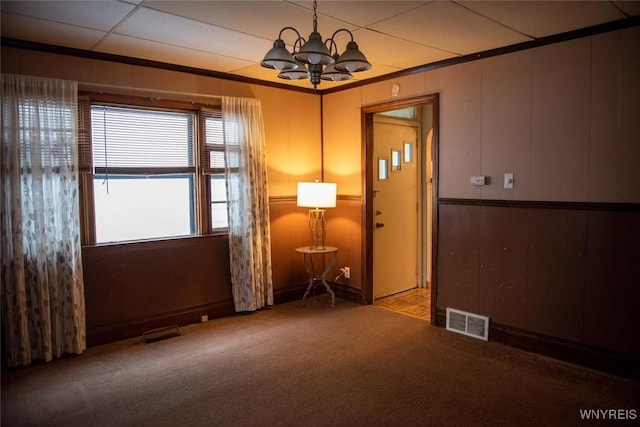 unfurnished room featuring carpet, ornamental molding, and a notable chandelier