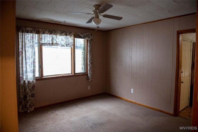 unfurnished room with ceiling fan, light colored carpet, and wood walls