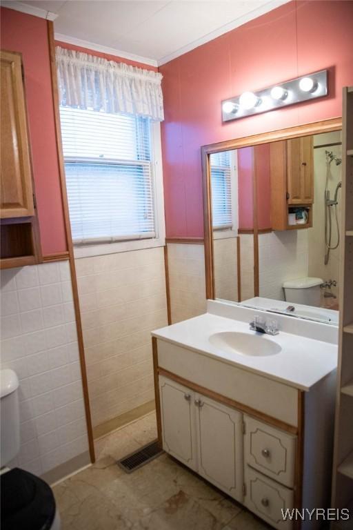 bathroom featuring vanity, tile walls, and toilet