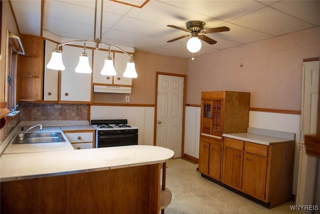 kitchen featuring sink, a drop ceiling, kitchen peninsula, decorative light fixtures, and white range with gas cooktop