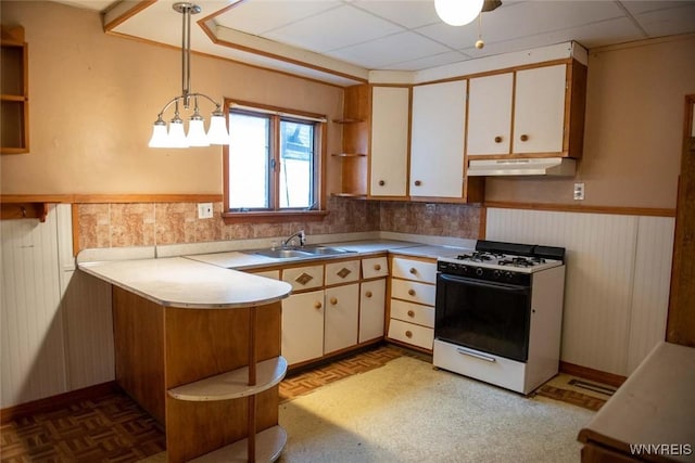 kitchen with white cabinetry, sink, white range with gas stovetop, decorative light fixtures, and a paneled ceiling