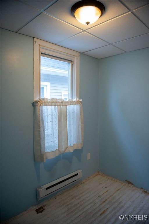 unfurnished room featuring a drop ceiling and a baseboard radiator