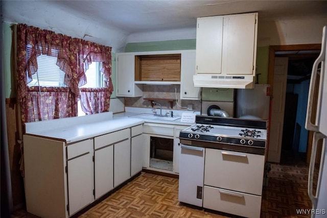 kitchen with white appliances, light parquet floors, sink, vaulted ceiling, and white cabinetry