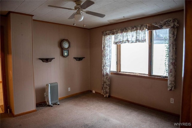 carpeted spare room with radiator, ornamental molding, and ceiling fan