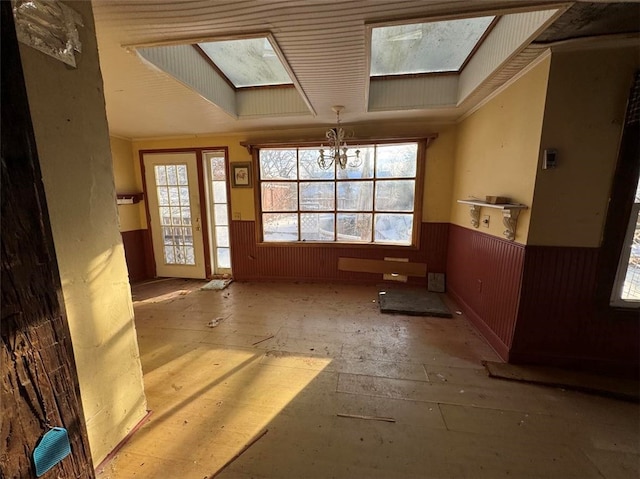 misc room with a chandelier, a skylight, and wood walls