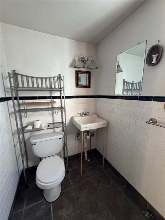 bathroom featuring tile patterned flooring, toilet, tile walls, and sink