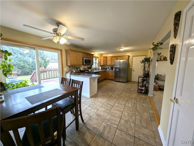 kitchen with ceiling fan, stone countertops, kitchen peninsula, and appliances with stainless steel finishes