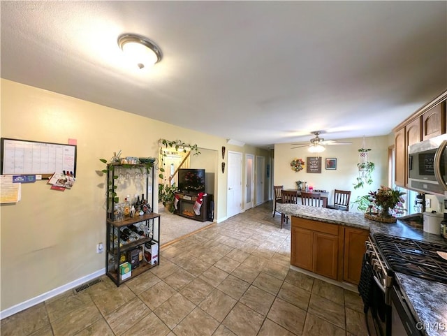 kitchen featuring ceiling fan, appliances with stainless steel finishes, and dark stone counters