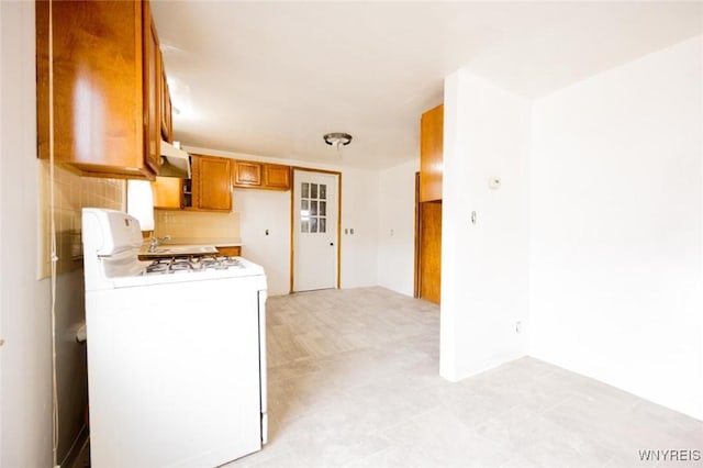 kitchen with white gas stove, light tile patterned flooring, and backsplash