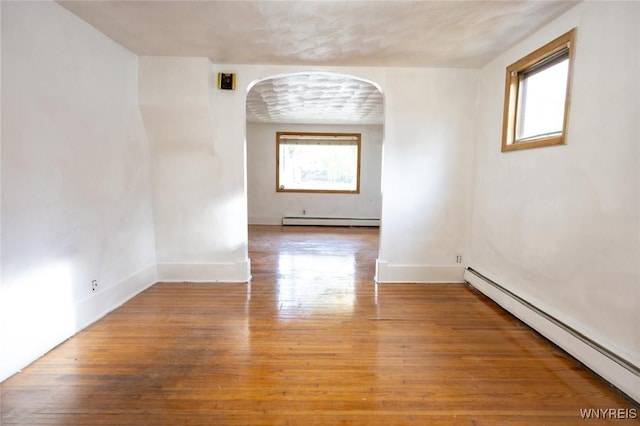 spare room featuring hardwood / wood-style flooring and a baseboard heating unit