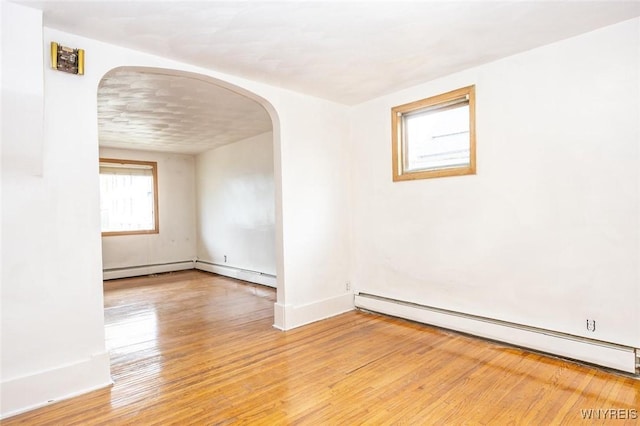 spare room featuring a baseboard radiator and light hardwood / wood-style floors