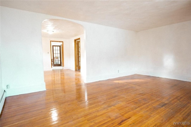 unfurnished room featuring hardwood / wood-style floors and baseboard heating