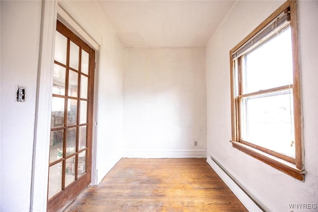 empty room with light hardwood / wood-style flooring and a baseboard heating unit